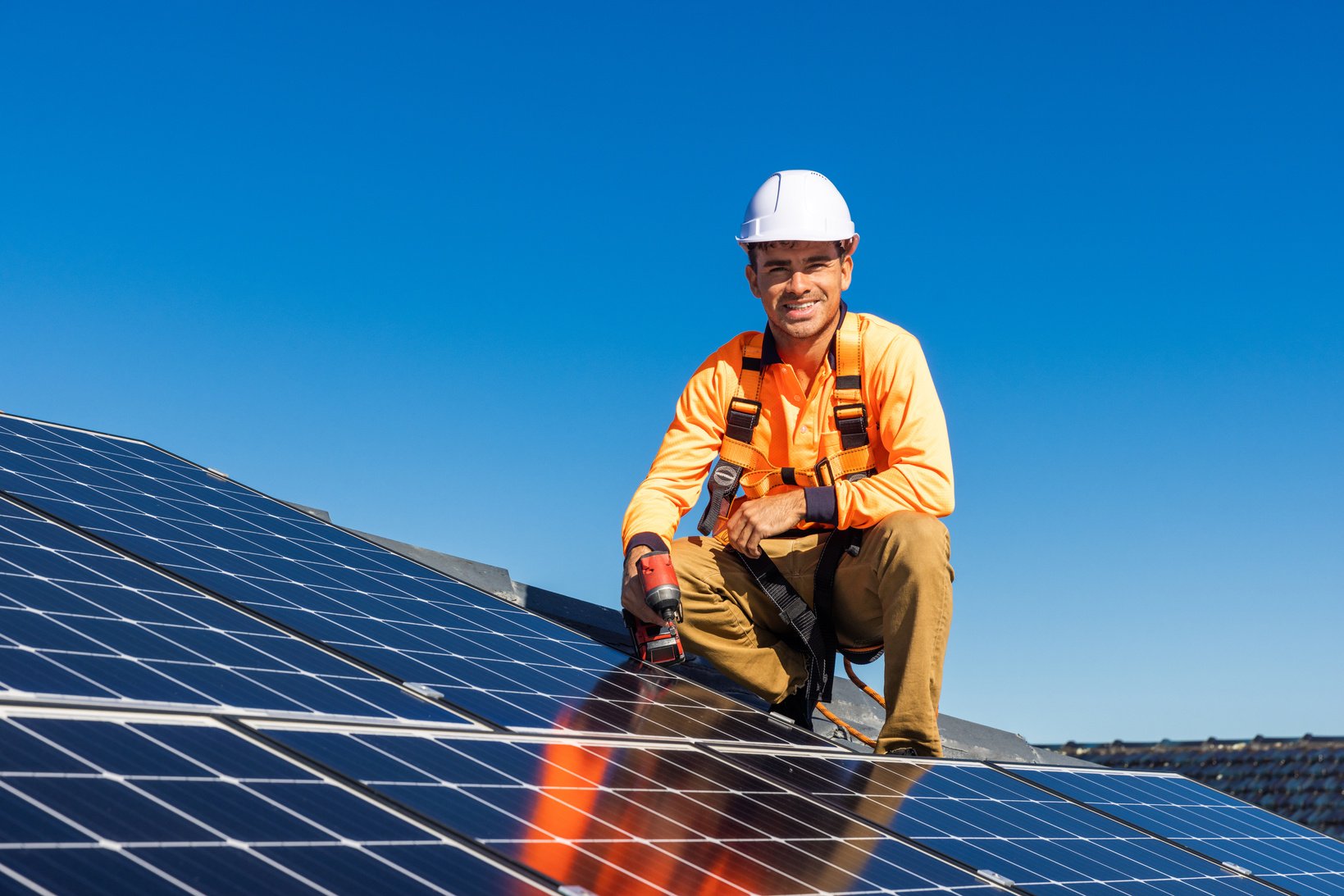 Solar panel technician with drill installing solar panels